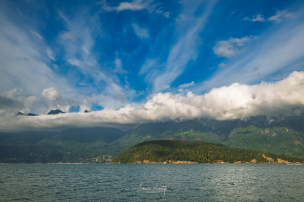 A spectacular view of a partially cloud-covered Brunswick Mountain and West Lion from just off Bowyer Island in British Columbia