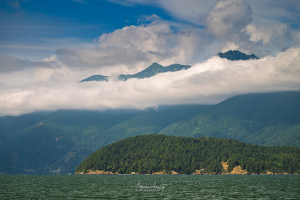 A spectacular view of a partially cloud-covered Brunswick Mountain and West Lion from just off Bowyer Island in British Columbia